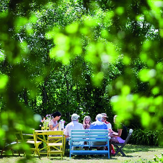 Familj fikar i lummig trädgård