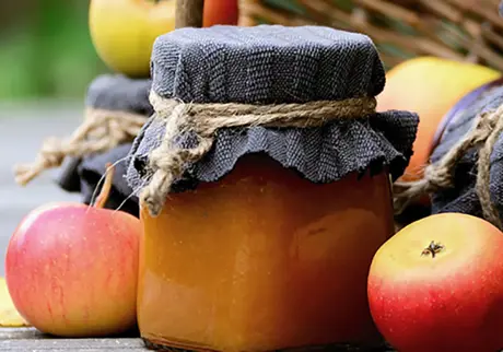 Äpplen och burk med äppelmos på bord