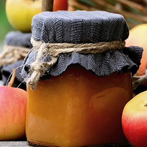 Äpplen och burk med äppelmos på bord