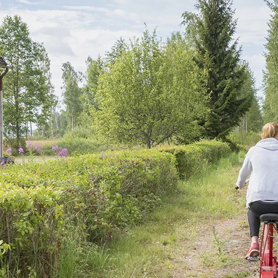 Människor cyklar förbi röd stuga