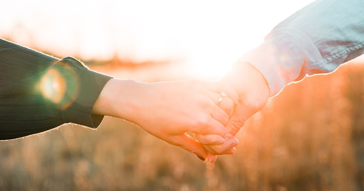 Par håller handen i solnedgången