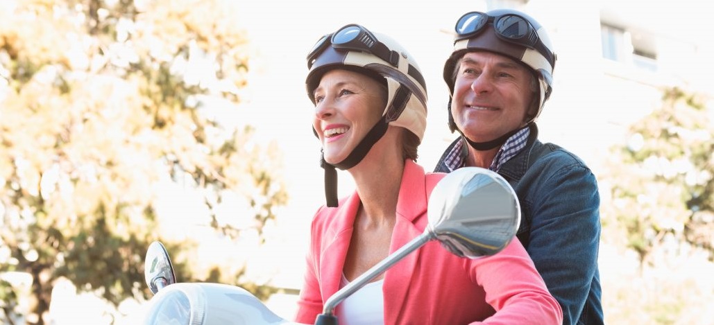 Äldre par glada på moped