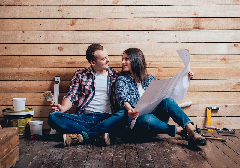 Par sitter på golvet med ritning och verktyg