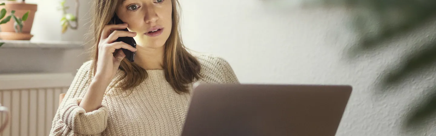 Kvinna pratar i telefon och använder laptop