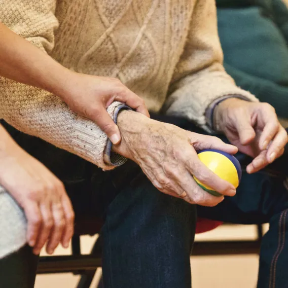 Kvinna håller i äldre mans hand som håller i en boll