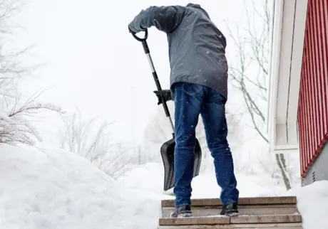 Man skottar bort snö vid trappa
