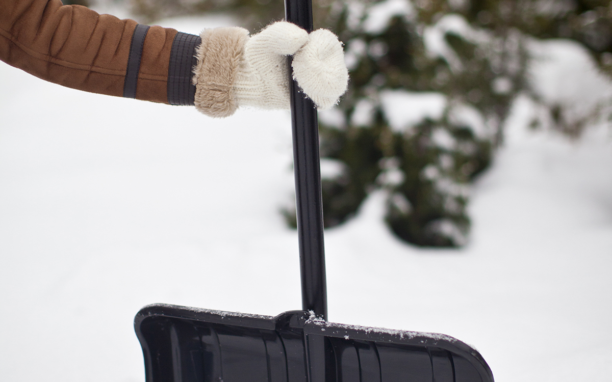 Hand ed vante på snöskyffel