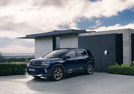 Blå Citroën under laddning invid husvägg
