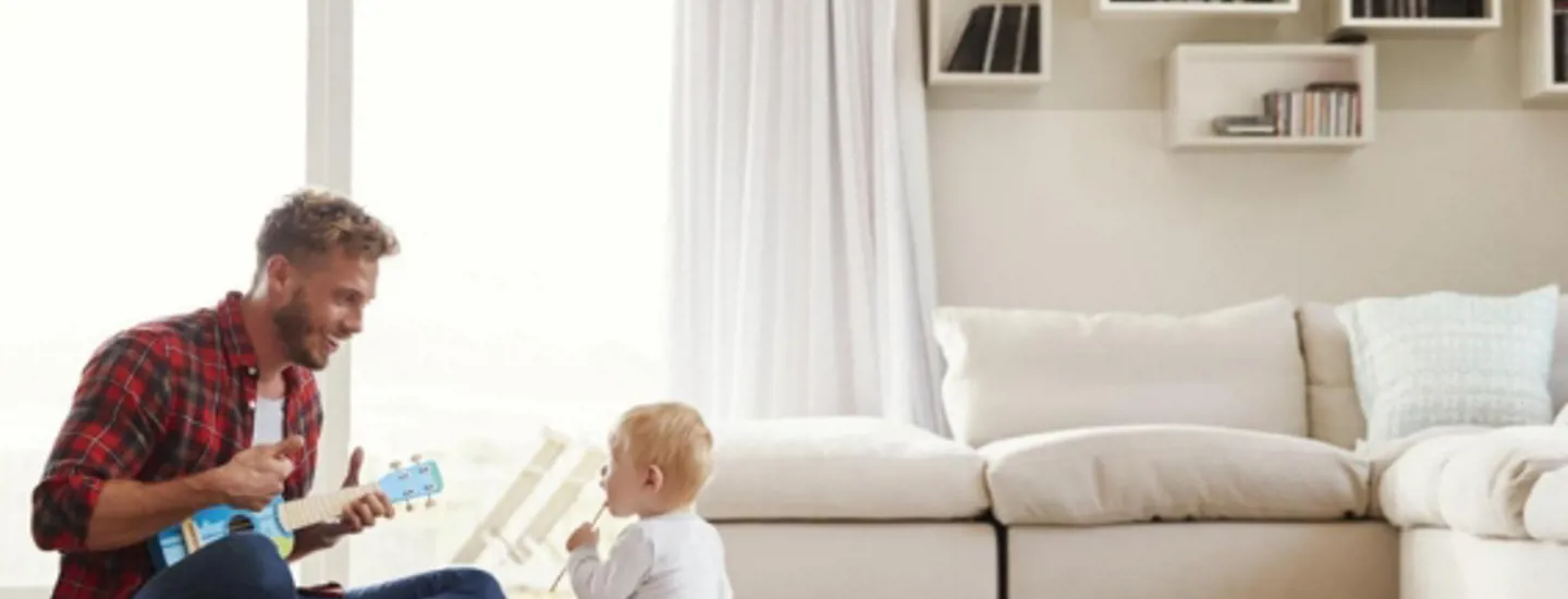 Pappa och barn sitter i ett vardagsrum med en luftvärmepump
